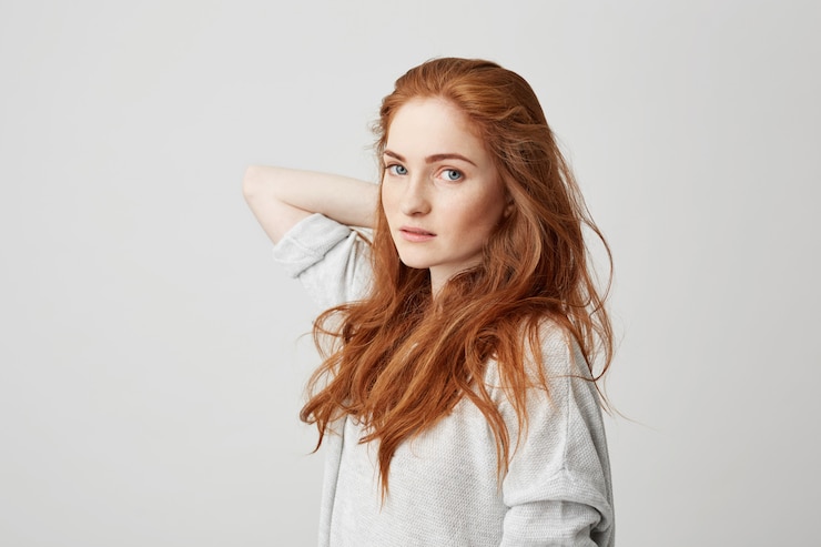 Free Photo portrait of young pretty ginger girl with freckles touching hair .