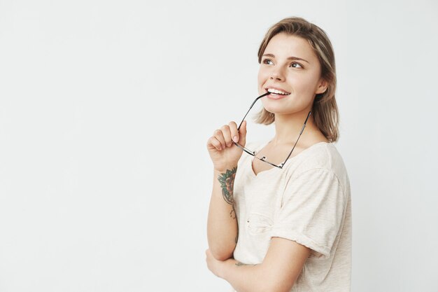 Portrait of young pretty girl smiling thinking dreaming biting glasses .