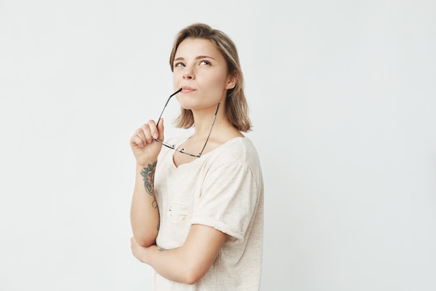 Portrait of young pretty girl smiling thinking dreaming biting glasses .