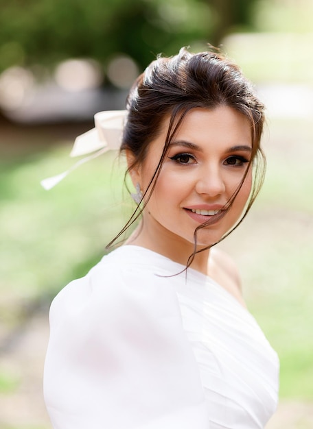 Portrait of young pretty girl with brunette tied hair dark brown eyes naturally make up sincere smiling and looking at camera while posing outdoor