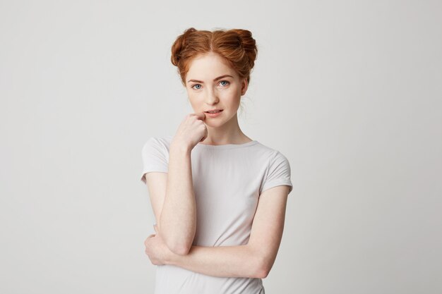 Portrait of young pretty girl with red hair touching chin .