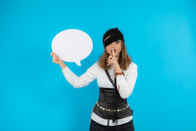 Portrait of young pretty pirate girl holding idea board and gesture silent. High quality photo