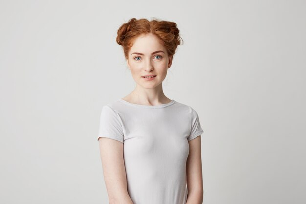 Portrait of young pretty redhead girl with buns smiling .