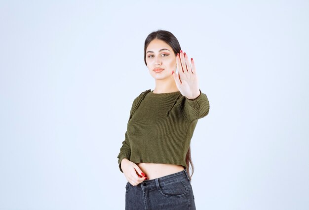 Portrait of a young pretty woman model standing and doing stop sign.