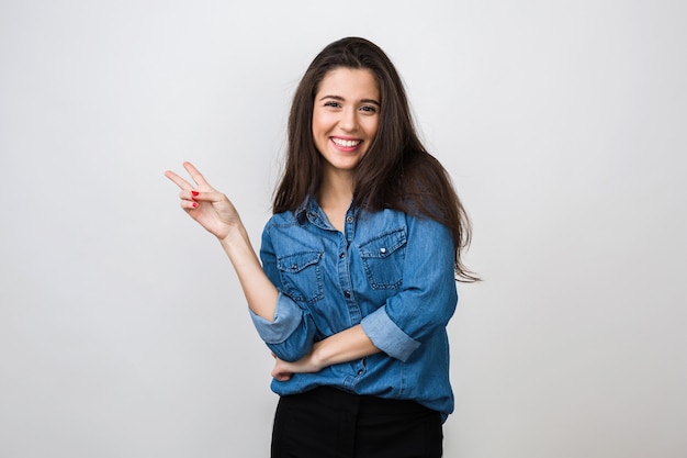 Portrait of young pretty woman smiling in blue denim shirt , happy, positive mood, isolated, sincere smile, long hair, showing peace sign, positive mood