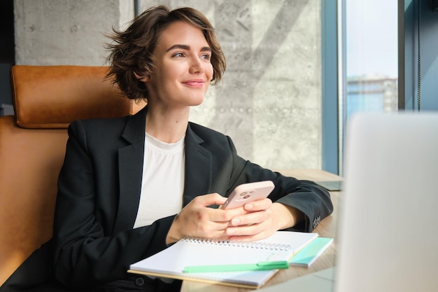 Portrait of young professional saleswoman businesswoman in suit sitting in office at her company