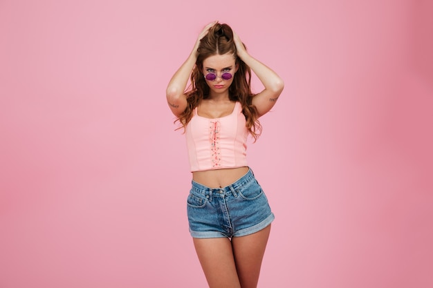 Portrait of young readhead pretty woman in glasses and summer wear, touching her hair
