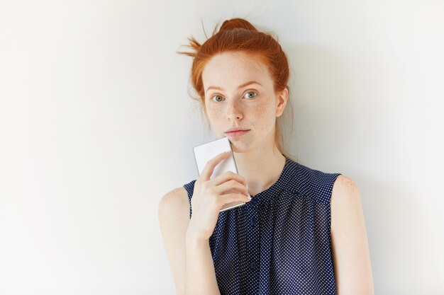 Portrait of young red-haired woman holding phone