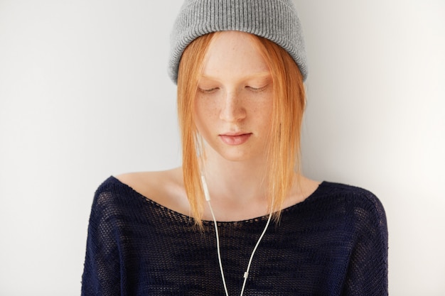 Portrait of young red-haired woman with headphones