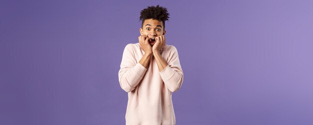 Free photo portrait of young scared guy watching really scary movie horror alone gasping screaming and hold han