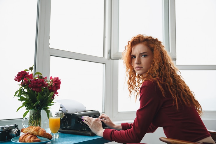 Free Photo portrait of a young seriousredheaded woman typing