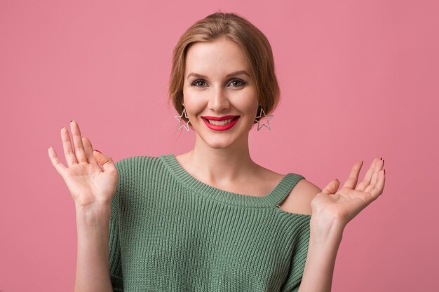 Portrait of young sexy beautiful woman isolated on pink background, smiling, elegant style, red lips, spring fashion trend, happy face expression, looking in camera, positive emotion, holding hands up