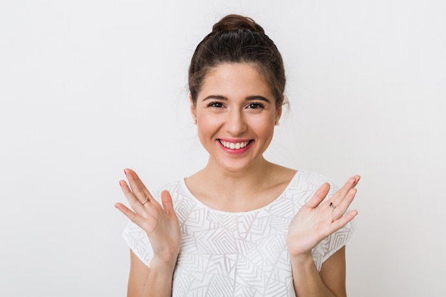 Portrait of young sincere smiling woman in white blouse, positive surprised face expression, happy, holding hands up, open palms, 
