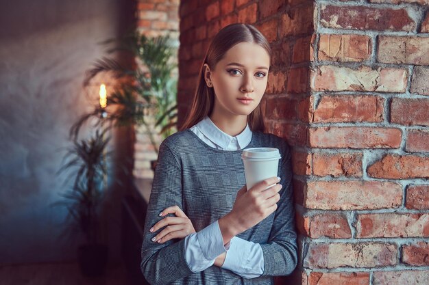 Portrait of a young slim sensual girl in a gray dress leaning ag