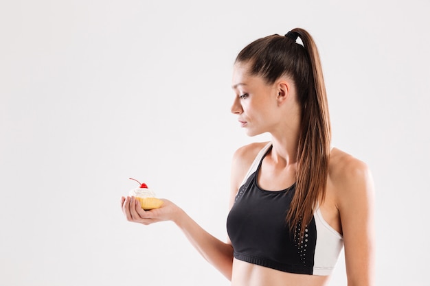 Free photo portrait of a young slim sportswoman holding cupcake