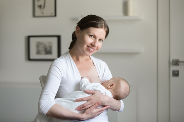 Foto gratuita ritratto di una giovane donna sorridente attraente che allatta al seno un chi