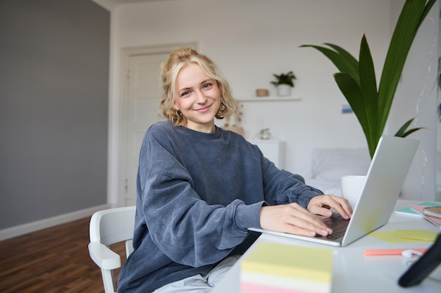 Portrait of young smiling beautiful woman student studying remotely in her room elearning using