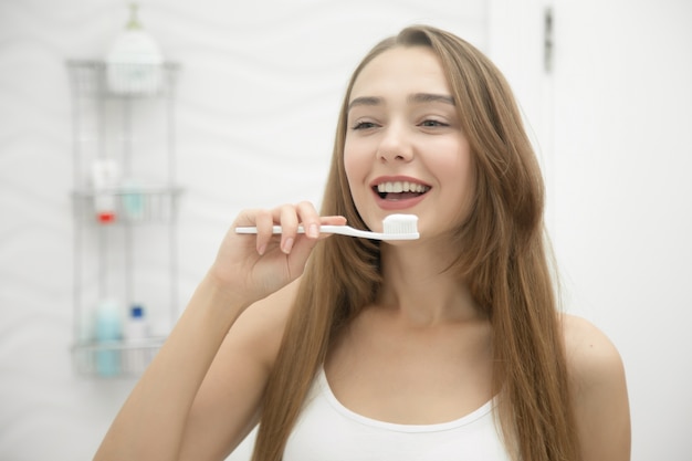 Free photo portrait of a young smiling girl cleaning her teeth