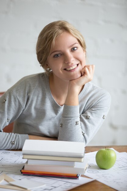 Portrait of a young smiling girl with books and apple
