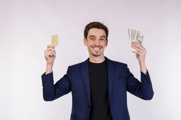 白い背景の上に分離されたクレジットカードと現金を示す若い笑顔のハンサムなビジネスマンの肖像画