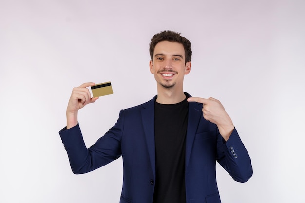 白い背景の上に分離されたクレジットカードを示す若い笑顔のハンサムなビジネスマンの肖像画