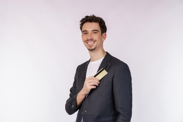 Portrait of Young smiling handsome businessman showing credit card isolated over white background