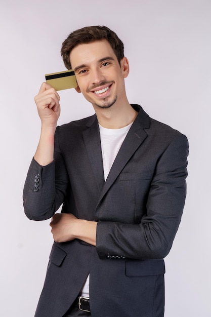 白い背景の上に分離されたクレジットカードを示す若い笑顔のハンサムなビジネスマンの肖像画