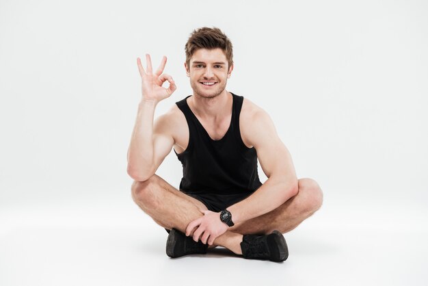 Portrait of a young smiling healthy fitness man sitting