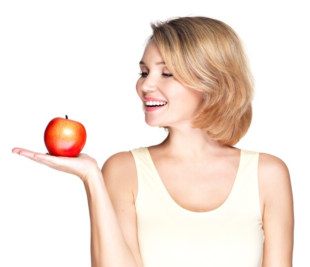 Portrait of a young smiling healthy woman with red apple isolated on white.