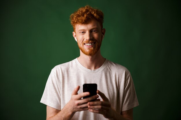 Portrait of young smiling redhead bearded young man, listening music with airpods