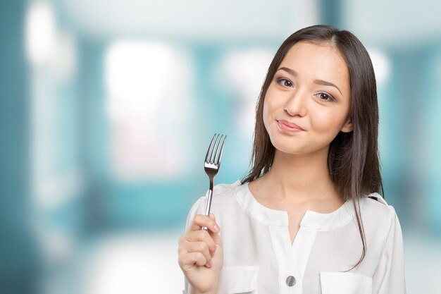 Portrait of young smiling woman with fork in her mouth