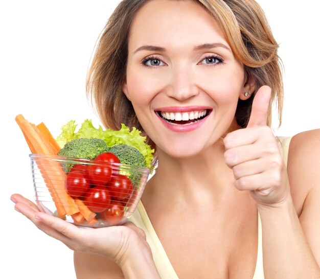 Portrait of a young smiling woman with a plate of vegetables - isolated on white.