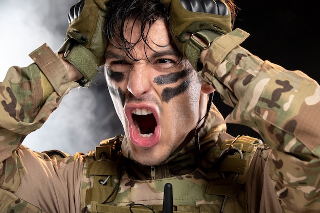 Free photo portrait of young soldier in camouflage on dark wall