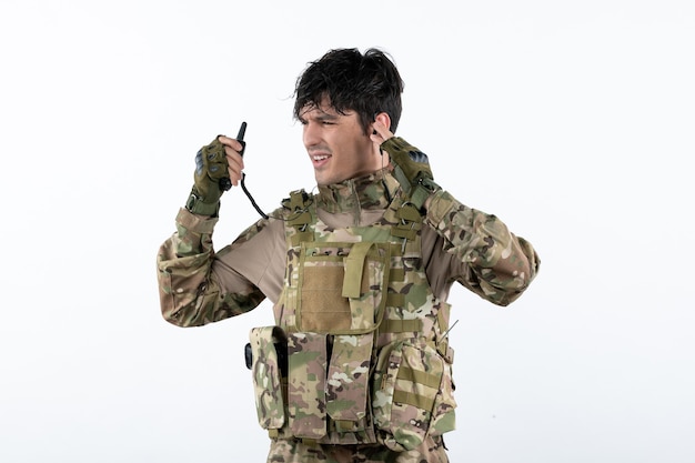 Portrait of young soldier in camouflage on white wall