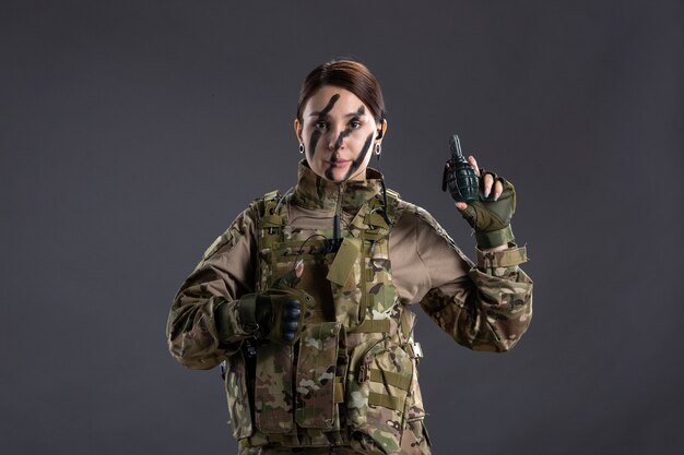 彼女の手に手榴弾の暗い壁とカモフラージュの若い兵士の肖像画