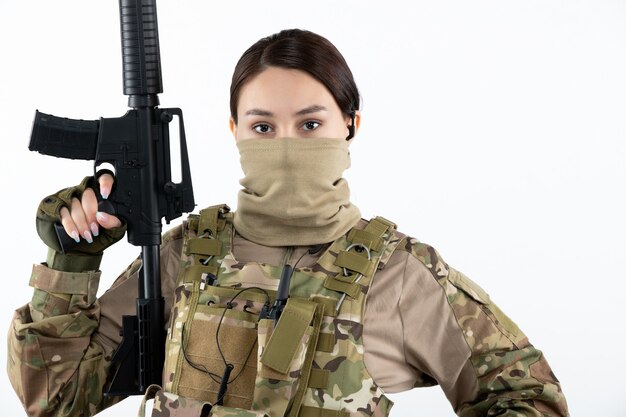 Free photo portrait of young soldier in camouflage with machine gun white wall