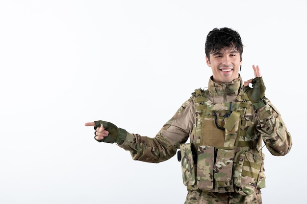 Portrait of young soldier in military uniform on white wall