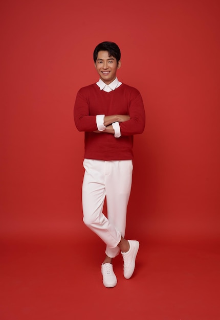 Free photo portrait young southeast asian man standing with crossed arms isolated on red background