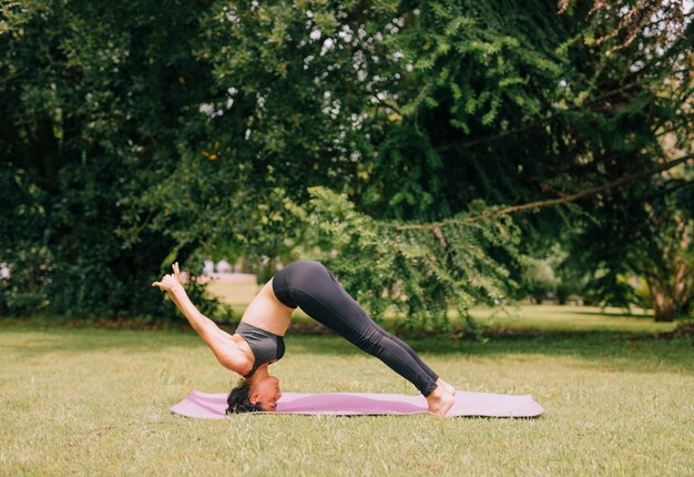 Portrait of young sporty attractive woman practicing yoga in the park