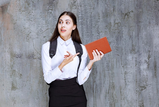 Portrait of young student in school outfit holding book and posing. High quality photo