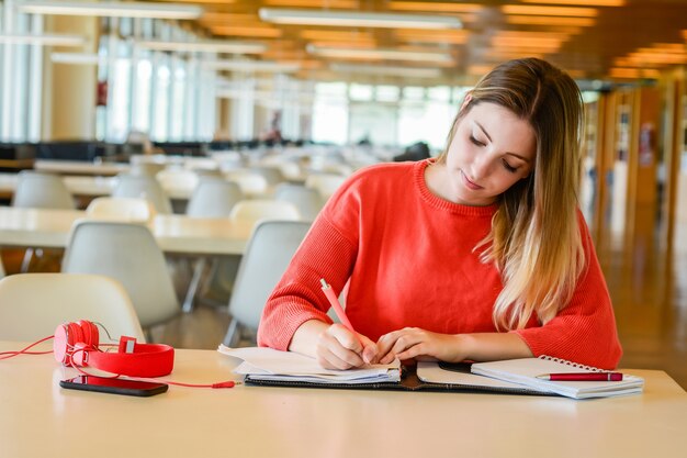 Portrait of young student studying at the university library. Education and lifestyle concept.