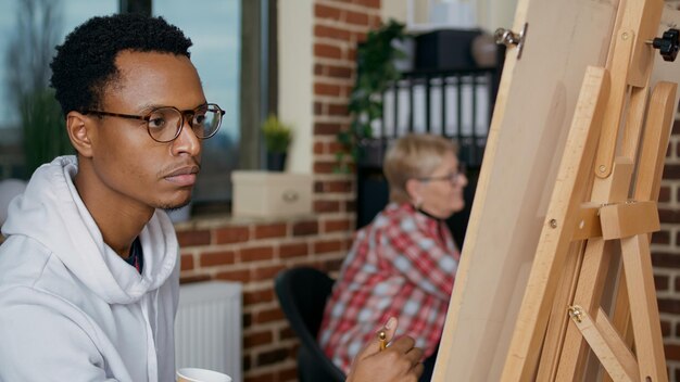 キャンバスに鉛筆を使って花瓶を描き、美術の授業で創造的なスキルを学ぶ若い学生の肖像画。教育の成長のためのクラフト機器でアートワークの図面を作成するための芸術的なワークショップ。