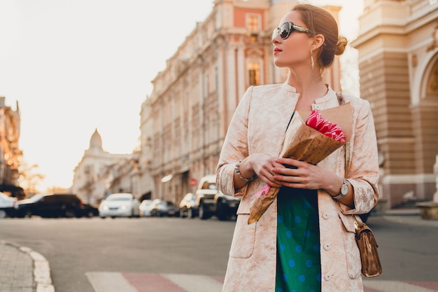 Portrait of young stylish attractive woman walking in city