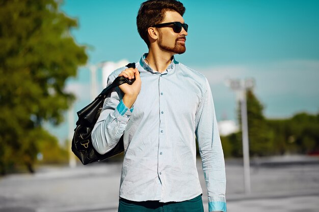 portrait of young stylish confident happy handsome  model man in hipster cloth with bag in the street, life style