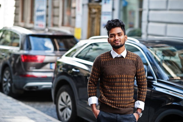 Portrait of young stylish indian man model pose in street against suv car