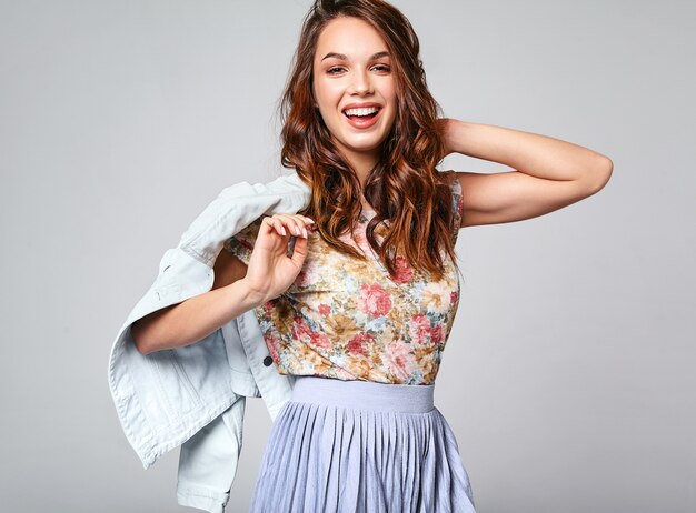 Portrait of young stylish laughing model in colorful casual summer clothes with natural makeup on gray