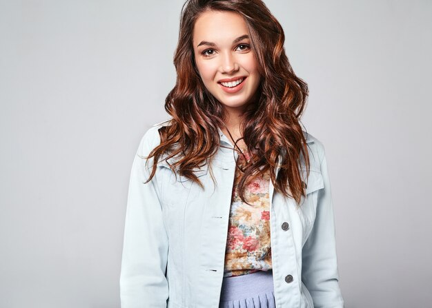 Portrait of young stylish laughing model in colorful casual summer clothes with natural makeup on gray