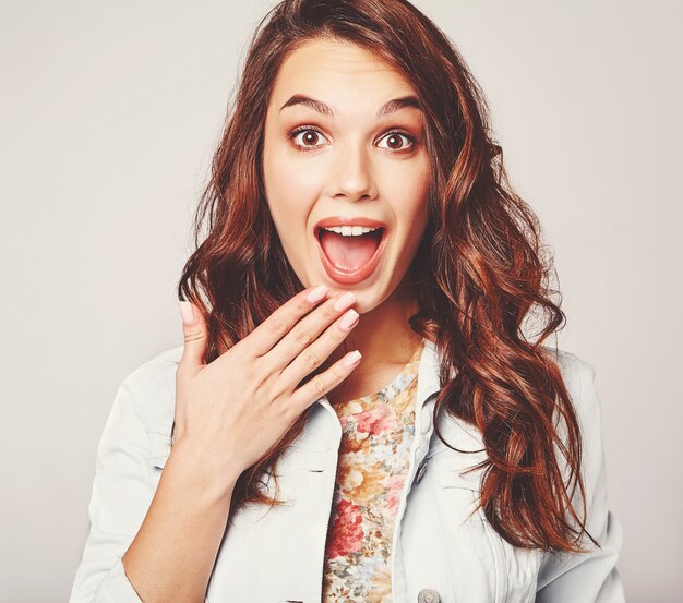 Portrait of young stylish laughing model in colorful casual summer clothes with natural makeup on gray