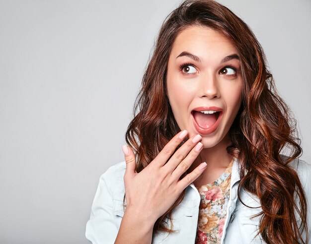 Portrait of young stylish laughing model in colorful casual summer clothes with natural makeup on gray