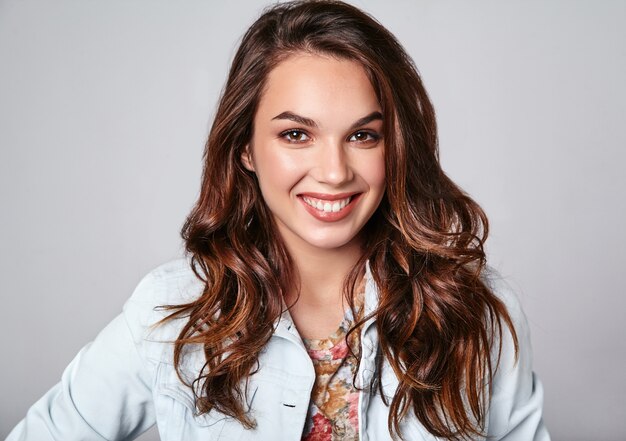 Portrait of young stylish laughing model in colorful casual summer clothes with natural makeup on gray